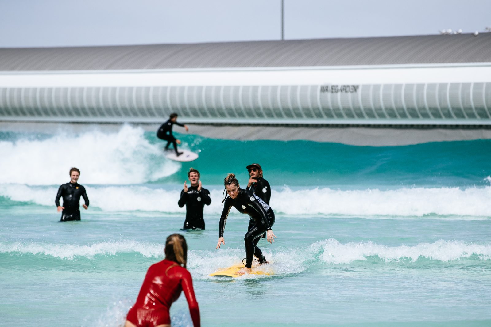 Surf coach guiding a learner on a wave at the surf pool